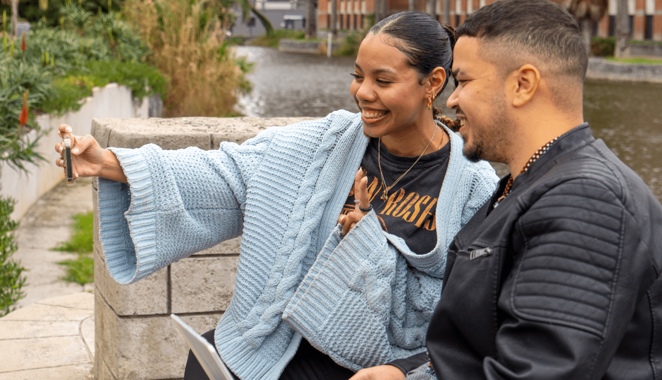 Two people smiling while taking a selfie outdoors, capturing a shared moment for social media content
