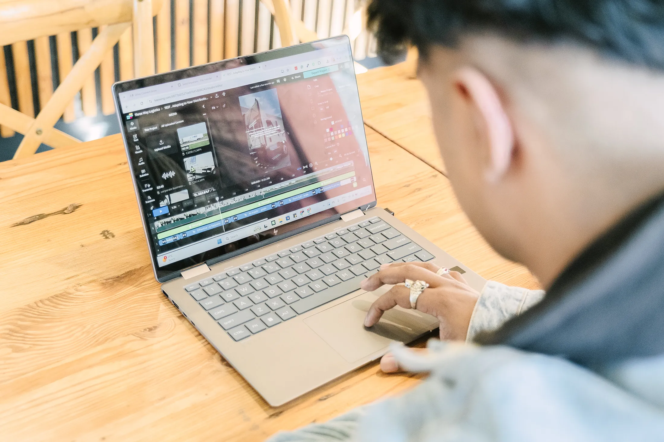 Digital Content Creation and Website Design Workflow Person editing a video project on a laptop at a wooden table, with a video timeline, media assets, and editing tools visible on the screen.
