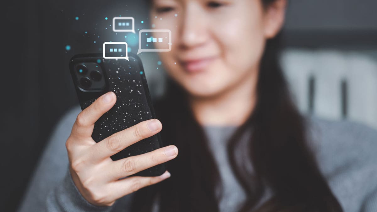 A lady texting on her phone with text symbols behind it
